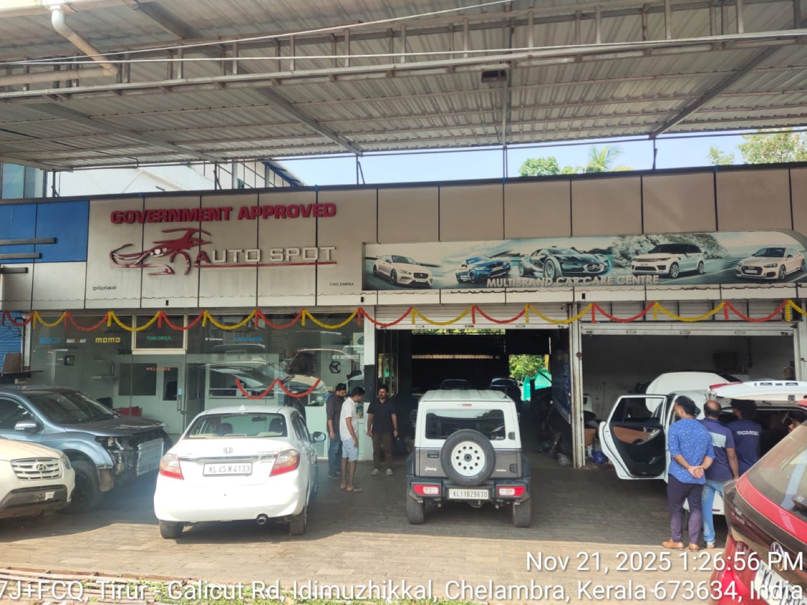Open service bays at the Auto Spot Malappuram workshop with a Maruti Dzire, a Mahindra Thar and other cars waiting for work