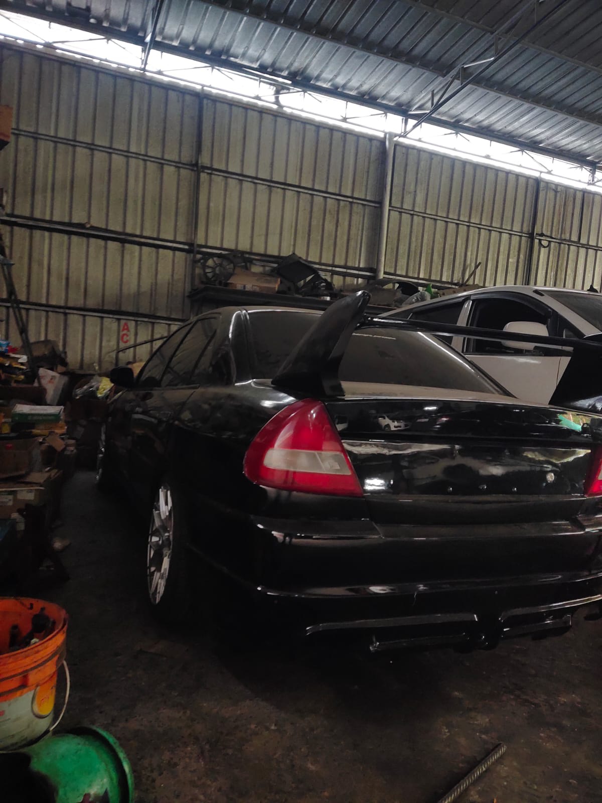 A freshly painted black Mitsubishi Lancer with its boot lid off in the body shop
