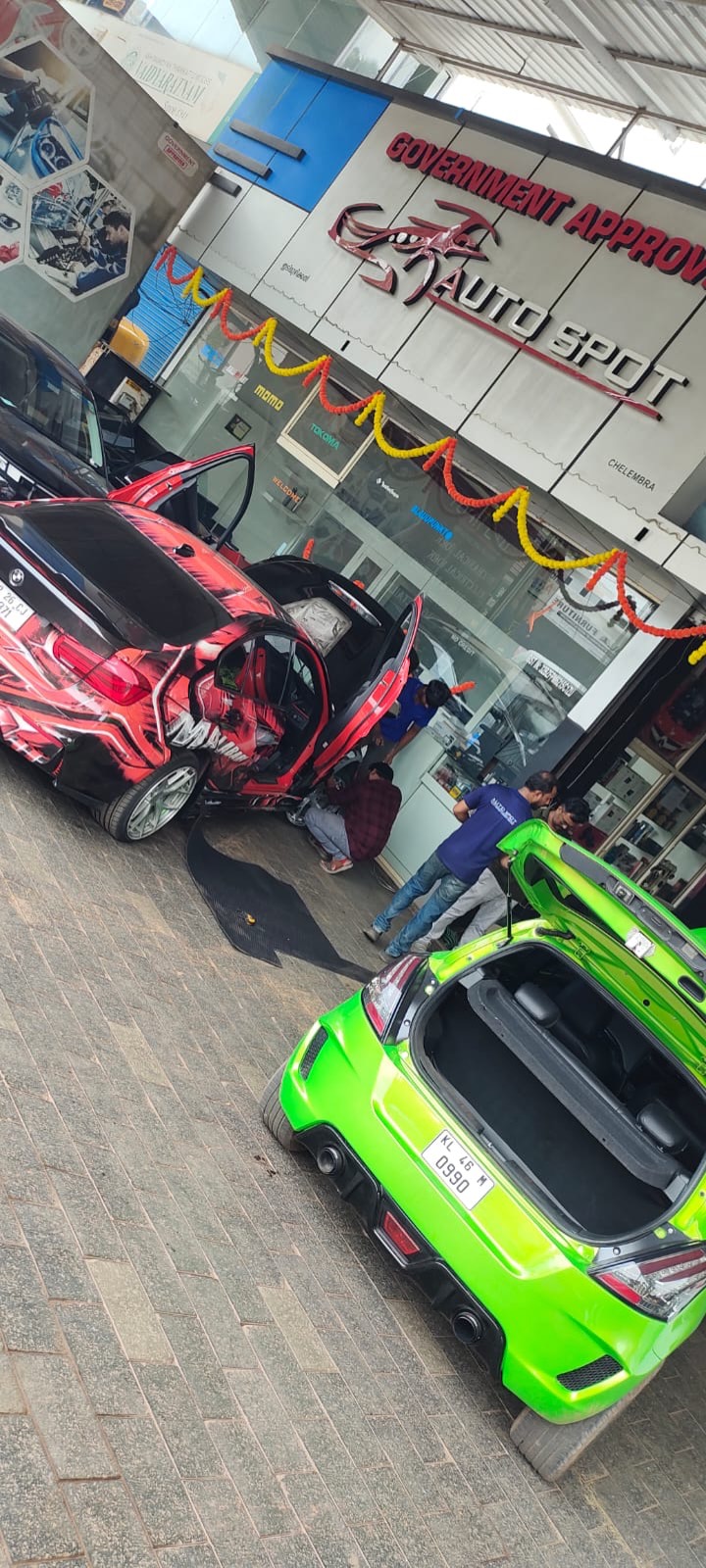 A wrapped BMW and a bright green modified hatchback parked outside the Auto Spot workshop